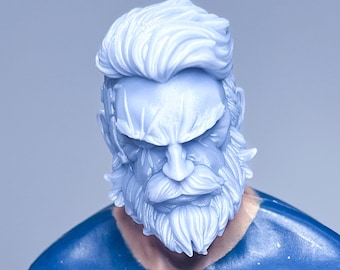 Op de afbeelding: Een close-up van een blauw plastic actifiguur hoofd met een witte baard en haar. De figuur heeft een serieuze uitdrukking.