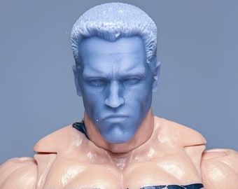 May include: A close-up of a plastic action figure with a blue head and a black eagle tattoo on its chest.