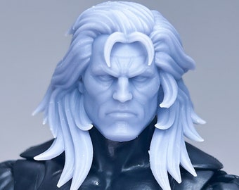 May include: A close-up of a grey plastic action figure head with long, flowing hair. The figure has a serious expression and a detailed face.