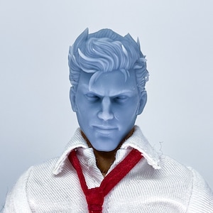 Op de afbeelding: Een grijs gebeeldhouwd hoofd met een kort, gestyled kapsel. Het hoofd draagt een wit overhemd met kraag en een rode stropdas.