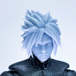 May include: A close-up of a plastic action figure head with spiky, light blue hair and a black jacket.