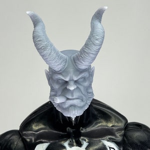 May include: A grey plastic action figure head with horns, a beard, and a cigar in its mouth.