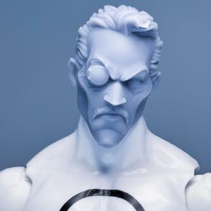 May include: A light blue figurine of a stern-faced man with a monocle, mustache, and slicked-back hair. The figure has a white torso with a black circle design. The background is a solid light blue.