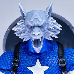 Puede incluir: Una cabeza de hombre lobo gris con una estrella azul y blanca en el pecho. La cabeza de hombre lobo tiene un hocico blanco y una boca grande abierta con dientes afilados. La estrella está sobre un fondo azul con un contorno blanco.