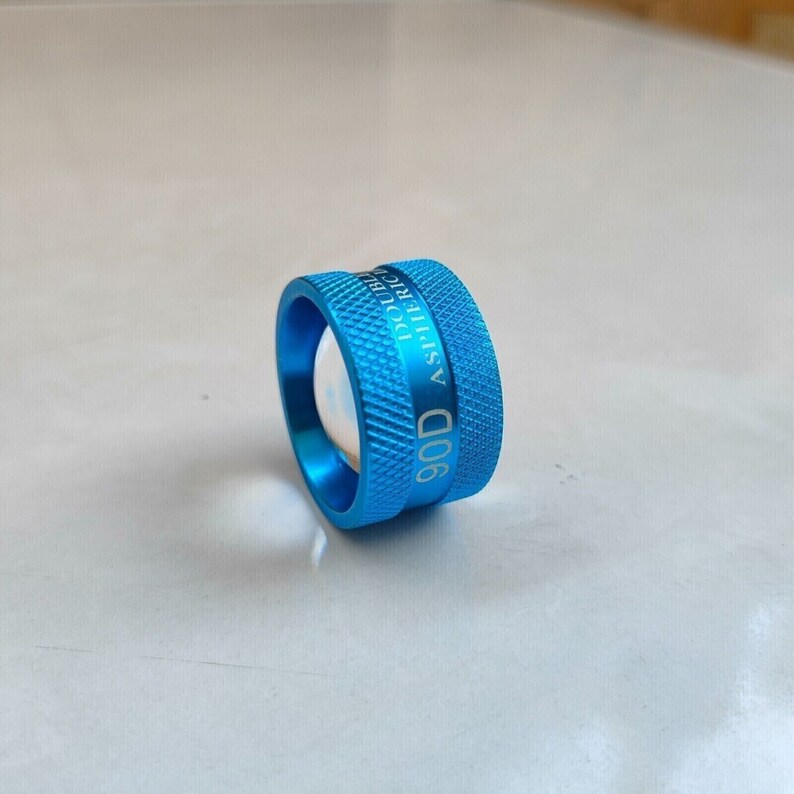 Op de afbeelding: Een blauwe metalen ring met de tekst "90D ASPHERIC DOUBLE" erop gegraveerd.