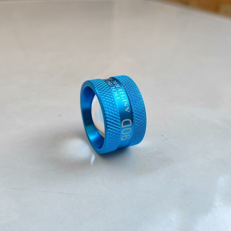 Op de afbeelding: Een blauwe metalen ring met de tekst "90D ASPHERIC DOUBLE" erop gegraveerd.