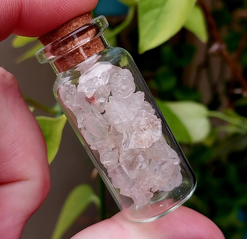 May include: A small glass bottle with a cork stopper filled with clear quartz crystals.
