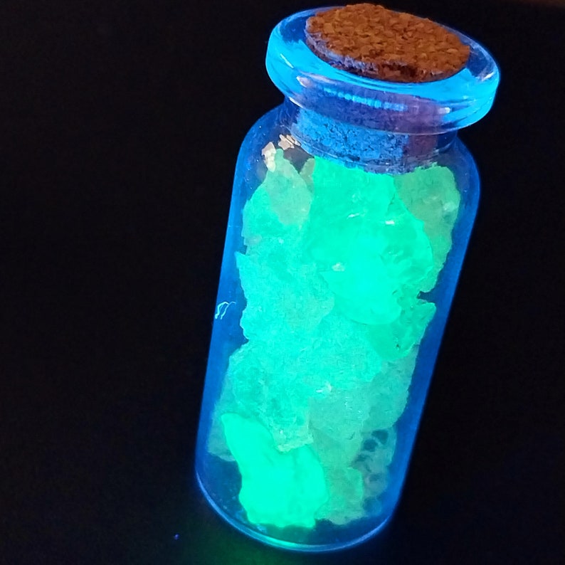 May include: A small glass bottle with a cork stopper filled with glowing green crystals.