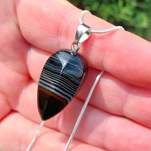 May include: A silver chain necklace with a black and white agate teardrop pendant.