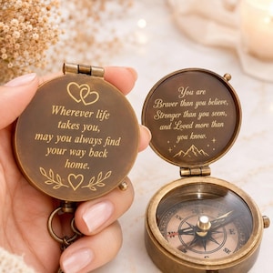 Pode incluir: Uma bússola redonda de latão em estilo antigo com tampa articulada. O exterior da tampa apresenta o texto gravado: Wherever life takes you, may you always find your way back home, com motivos de corações e folhas. O interior da tampa diz: You are Braver than you believe, Stronger than you seem, and Loved more than you know, com ícones de montanhas e estrelas.