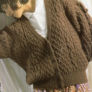 May include: A brown knitted cardigan with a cable knit pattern. The cardigan has a V-neck and is worn over a white shirt. The cardigan is 30-38 inches in size. Teens sizes are included. Price code B 8425.