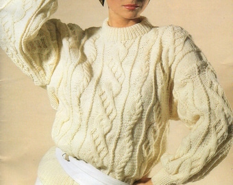 May include: A white cable knit sweater with a round neckline and long sleeves. The sweater is worn with a white belt and a white skirt.