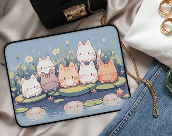 Könnte beinhalten: Eine blaue Laptoptasche mit einer bunten Illustration von Comic-Katzen, die auf Seerosen sitzen. Die Katzen sind in verschiedenen Orangetönen, Weiß und Braun.
