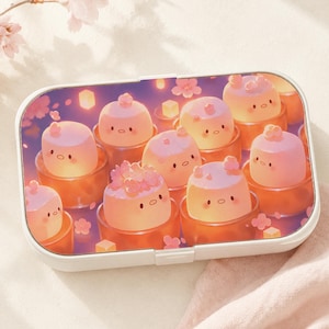 May include: A rectangular white lunch box featuring a printed graphic of multiple light pink, round, cartoon-like characters sitting in individual orange bowls, surrounded by small pink cherry blossom petals and glowing yellow square lights.