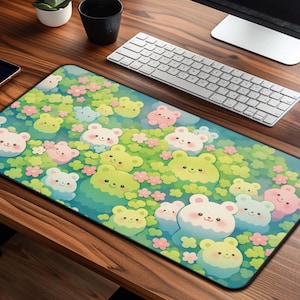 May include: A rectangular mousepad featuring a whimsical design of cartoon bears in shades of yellow, pink, and white, set against a backdrop of green foliage and small pink flowers. The mousepad is on a wooden desk with a keyboard and mouse.