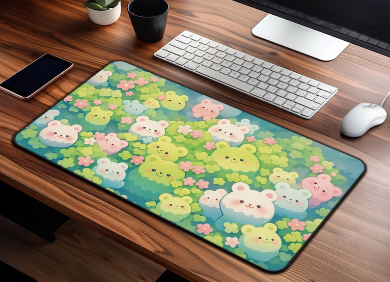 May include: A rectangular mousepad featuring a whimsical design of cartoon bears in shades of yellow, pink, and white, set against a backdrop of green foliage and small pink flowers. The mousepad is on a wooden desk with a keyboard and mouse.