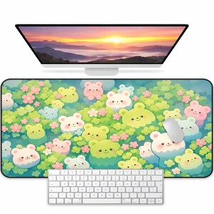 May include: A rectangular mouse pad featuring a colorful illustration of cartoon bears in shades of green, pink, and white, surrounded by flowers. A white computer mouse rests on the pad, with a white keyboard below and a computer monitor above.
