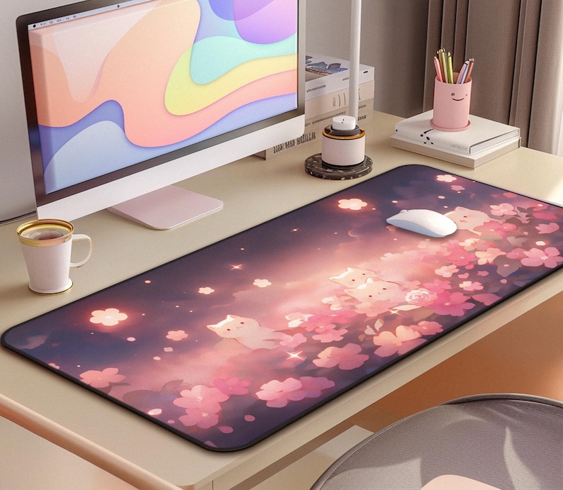 May include: A rectangular mouse pad featuring a whimsical design of white cat figures among pink cherry blossoms and glowing lights against a gradient purple and pink background. A white computer mouse sits on the pad.