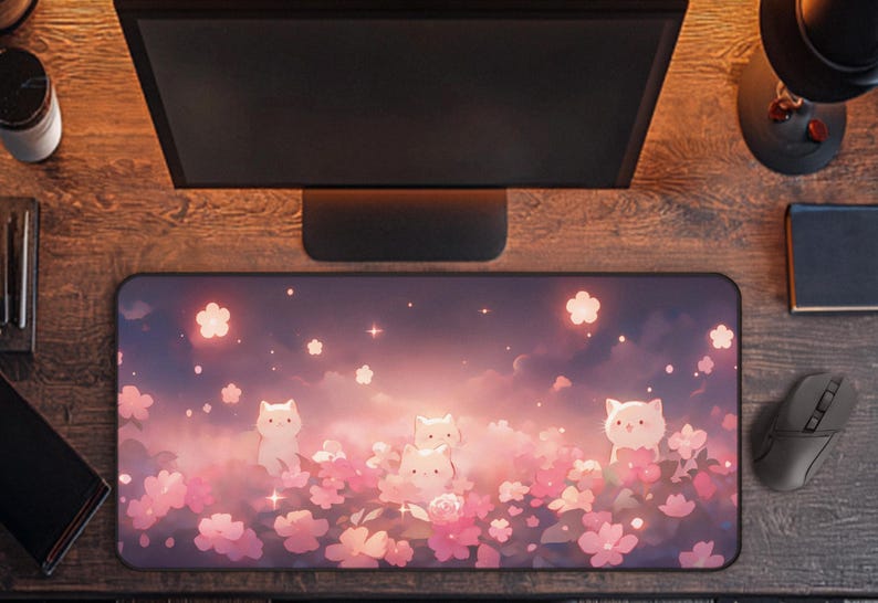 May include: A rectangular mousepad featuring a whimsical design of white cat characters amidst pink cherry blossoms and a dreamy sky. The pad is designed for computer use and is surrounded by a wooden desk, a computer monitor, and a mouse.