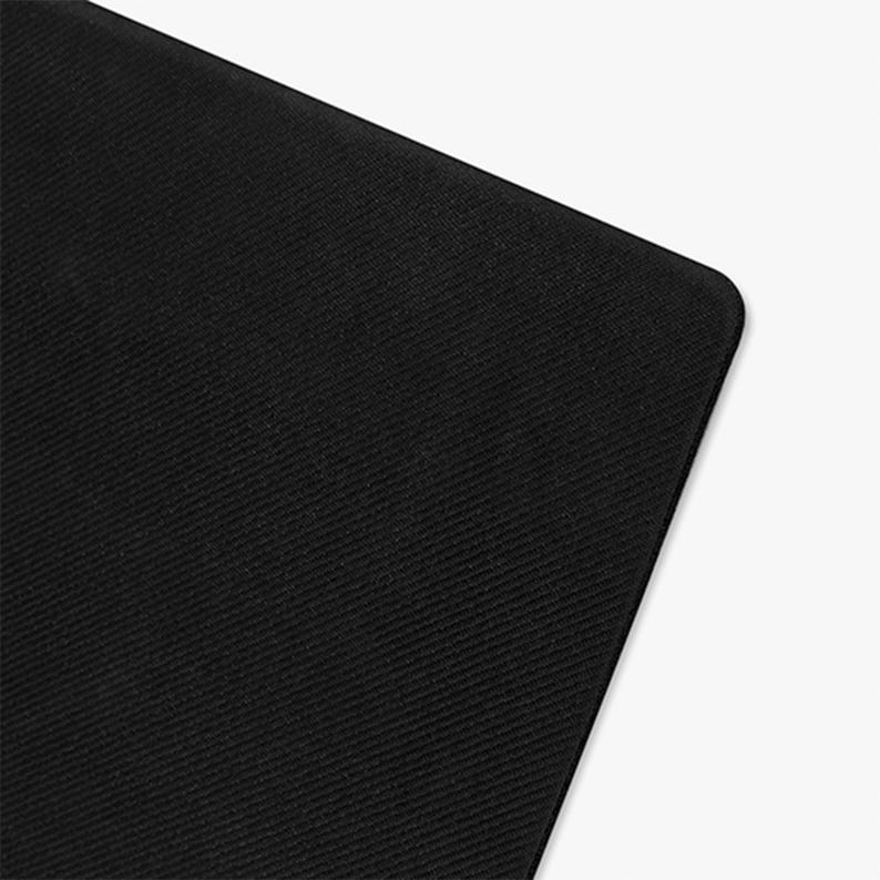 May include: A close-up of a black, rectangular object with rounded corners. The surface has a subtle, diagonal ribbed texture. The object is set against a white background.