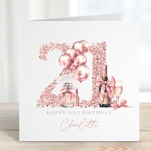 May include: A white birthday card with a rose gold glitter "21" design, balloons, perfume, lipstick, champagne, and a glass. The card reads "Happy 21st Birthday" and "Charlotte" in a delicate script.