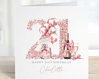 Op de afbeelding: Een witte verjaardagskaart met een roségouden glitter "21" ontwerp, ballonnen, parfum, lippenstift, champagne en een glas. De kaart leest "Happy 21st Birthday" en "Charlotte" in een delicaat script.