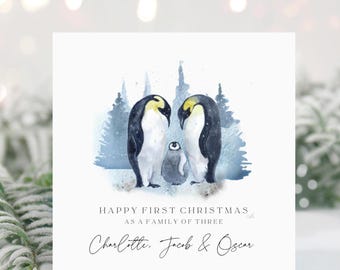 May include: A Christmas card with a watercolor illustration of two penguins and a baby penguin in a snowy forest. The text reads "Happy First Christmas as a family of three Charlotte, Jacob & Oscar."