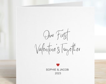 May include: A white card with black calligraphy that reads "Our First Valentine's Together" with a small red heart and the names "Sophie & Jacob" and the year "2023" printed below.