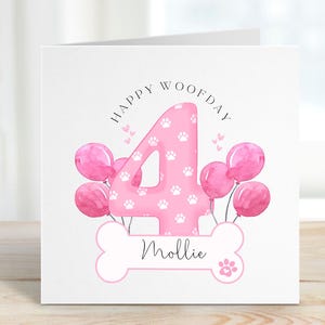May include: Pink birthday card featuring a large number 4 with paw prints, surrounded by pink balloons. The card reads "Happy Woofday" and has a bone with the name "Mollie" on it.
