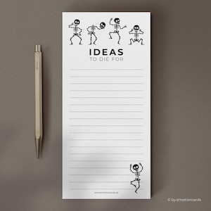 Può includere: Un blocco note bianco con illustrazioni di scheletri neri e la scritta "IDEAS TO DIE FOR". Il blocco note ha pagine a righe e una penna d'argento è accanto. Per prendere appunti.