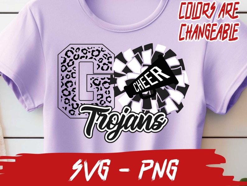 May include: A purple t-shirt with a black and white design. The design features a large letter "G" with a leopard print pattern, a cheerleading pom-pom, and a megaphone with the word "CHEER" on it. The text "Trojans" is written in a black cursive font below the design. The text "COLORS ARE CHANGEABLE" is written in red at the top of the image. The text "SVG - PNG" is written in red at the bottom of the image.