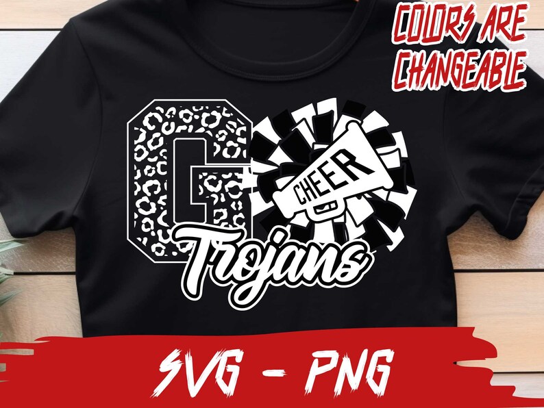 May include: Black and white graphic design featuring a cheerleading megaphone with the word "CHEER" on it, a large letter "G" with a leopard print pattern, and the word "Trojans" in a stylized font. The text "COLORS ARE CHANGEABLE" appears above the design. The design is on a black t-shirt.