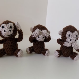 Puede incluir: Tres monos de crochet marrones, cada uno cubriendo una parte diferente de su cara. Un mono se tapa los ojos, otro se tapa las orejas y el tercero se tapa la boca.
