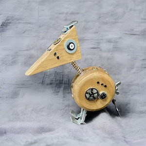 May include: A wooden bird sculpture with a whimsical design. The bird has a long beak, a round body, and is decorated with metal gears and screws. The bird is painted in a natural wood color.