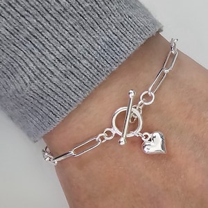 Puede incluir: Un brazalete de plata con un dije de coraz&oacute;n y un cierre de palanca.