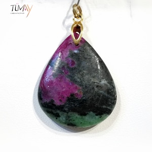 Peut inclure: Un pendentif en forme de larme avec une pierre précieuse verte, noire et rose. Le pendentif est en or et possède un bélière pour l'attacher à une chaîne.