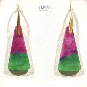 Puede incluir: Un par de pendientes colgantes con ganchos dorados y colgantes triangulares. Los colgantes están divididos en secciones rosa y verde. Los pendientes se exhiben sobre una superficie blanca. La marca "TUMAY CREATIONS" es visible.