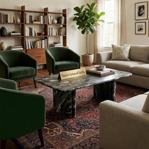 May include: A living room scene featuring a marble coffee table, green velvet armchairs, and a beige sofa. A patterned rug and a wooden bookshelf filled with books and decor complete the space. The sign on the table reads "SamisArtandCrafts."
