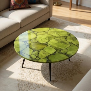 May include: A round coffee table with a vibrant green, stone-like top and black metal legs. The table's surface features a unique pattern of green and black veining, adding a touch of natural elegance to the living room setting.