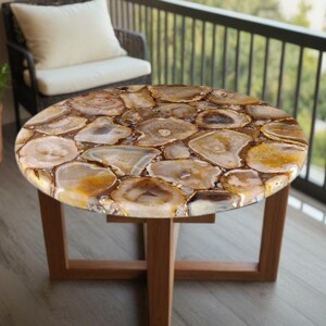 May include: A round, brown and white agate coffee table with a wooden base. The table top is made of polished agate slices, creating a unique and natural look.