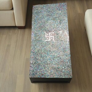 Puede incluir: Una mesa de centro negra con una tapa hecha de azulejos de nácar iridiscente. La mesa tiene un diseño decorativo en el centro de la tapa.