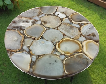 May include: Round table with a top made of agate slices in shades of brown, white, and gray. The table has a metal base.