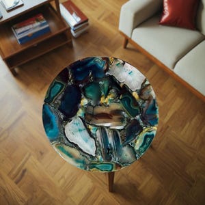 May include: A round, agate table top with a variety of blue, green, and brown agate pieces. The table top is set on a wooden floor.