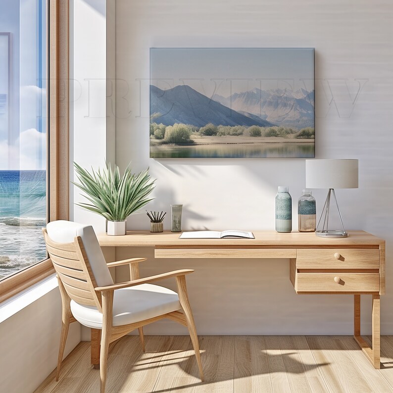 May include: A light wood desk with a matching chair, a landscape painting, and a window with a view of the ocean. The desk has a lamp, two decorative bottles, and a potted plant. The chair has a white cushion.