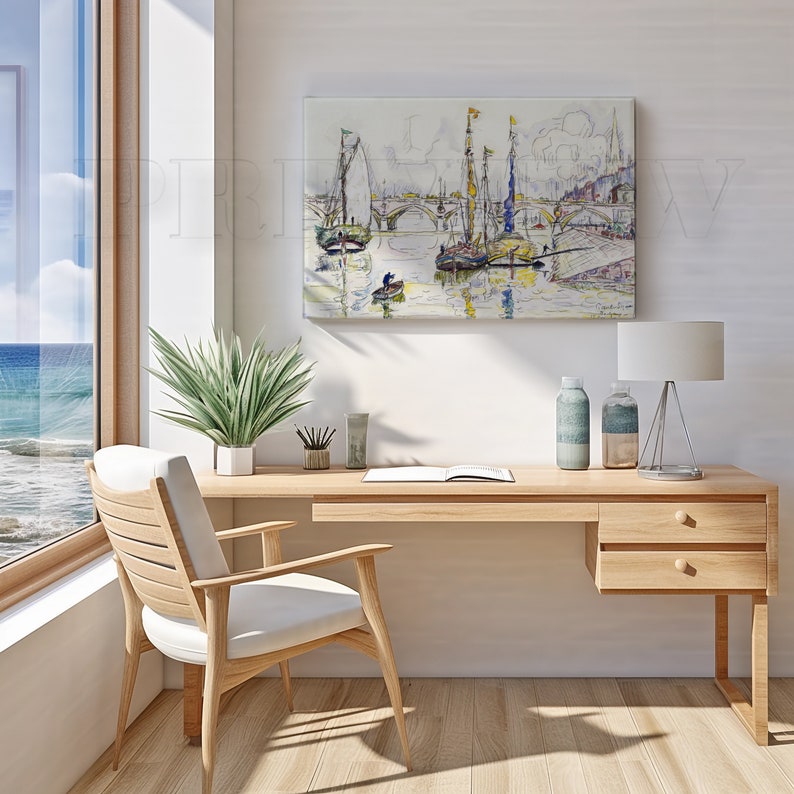 May include: A light wood desk with a white chair, a painting of boats on the water, and a window with a view of the ocean. The desk has a lamp, two bottles, and a plant.