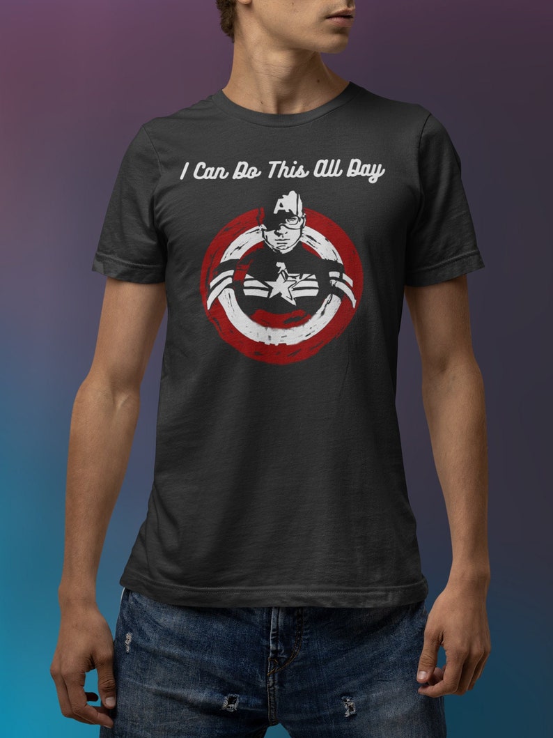 May include: Dark grey t-shirt with a Captain America graphic inside a red circle, and the text "I Can Do This All Day" above. The graphic features a star and shield design. The shirt is made of a soft material.