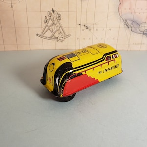 May include: Yellow and black toy train with red accents. The train has a single wheel and says "The Streamliner" on the side.