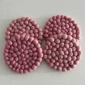 May include: Set of four pink felt coasters with a textured, bubble-like design.