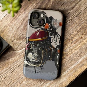 Pode incluir: Um close-up de uma motocicleta vermelha e dourada com um farol cromado e um fundo preto e branco. A motocicleta tem um motor grande e um design detalhado.