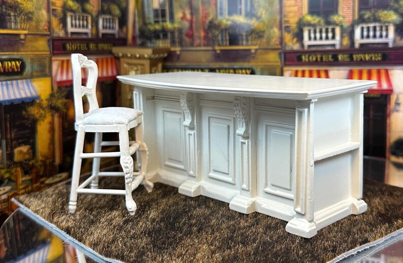 May include: White miniature kitchen island with a curved countertop and three cabinet doors. The island is accompanied by a white miniature bar stool with a carved design.